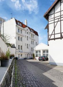 eine Kopfsteinpflasterstraße vor einem weißen Gebäude in der Unterkunft Hotel Alte Fabrik in Mettmann