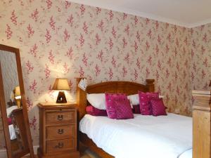 a bedroom with a bed with pink pillows and a lamp at Dairy Cottage - Beaufort Estate in Belladrum