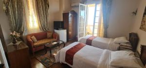 um quarto de hotel com duas camas e uma cadeira em Misr Hotel em Alexandria