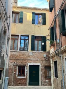 een bakstenen gebouw met een groene deur in een steegje bij Residenza Corte Antica in Venetië