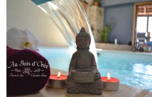 eine Statue eines Buddha mit Kerzen vor einem Pool in der Unterkunft AU BOIS D'ORÉE in Liré