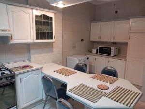 アンマンにあるAbdoun ground floor apartmentの白いキャビネットとテーブルと椅子のあるキッチン