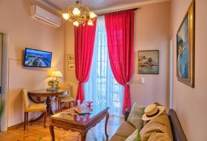 コルフ・タウンにあるAnesis Apartment Corfu Townのリビングルーム(赤いカーテン、テーブル付)