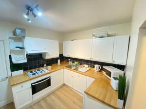 a kitchen with white cabinets and a wooden counter top at Elegant London home with Free 5G Wi-Fi, Garden, Workspace, Free Parking, Full Kitchen in Welling