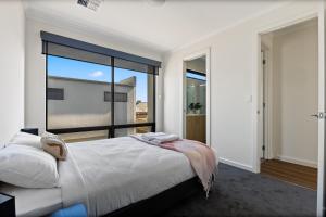 - une chambre avec un grand lit et une grande fenêtre dans l'établissement Swainson on College, à Port Adelaide