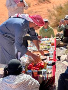a woman standing over a table with food on it at bedouin future camp in Wadi Rum