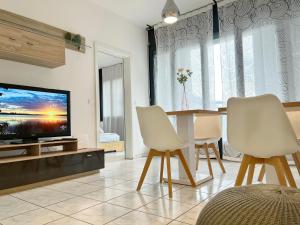 uma sala de estar com uma televisão e uma mesa e cadeiras em Bilocale con terrazzi Via Antonio Riva 3 by LR em Lugano