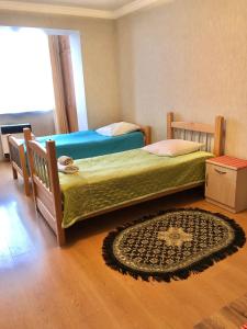 een slaapkamer met 2 bedden en een tapijt op de vloer bij 1 Bedroom Apartment in Tbilisi City