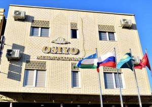 um edifício com três bandeiras à sua frente em Osiyo Hotel em Samarkand