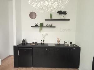 uma cozinha preta com um lavatório e prateleiras em The Manhattan Luxury suite em Jumet