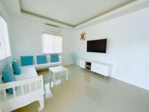 a white living room with a couch and a tv at Pool Villa Sattahip White House in Sattahip