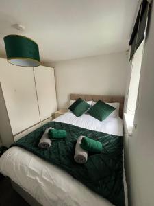 ein Schlafzimmer mit einem Bett mit grünen Kissen und grünen Handtüchern in der Unterkunft 1 Bed @ Factory Quater - Chard St in Nottingham