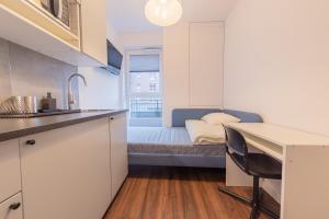 eine Küche mit einem Schreibtisch und ein Bett in einem Zimmer in der Unterkunft TinyRooms in Kattowitz