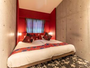 - une chambre avec un grand lit aux murs rouges dans l'établissement Hale Kyoto Tambaguchi#Tabist, à Kyoto