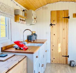 a kitchen with white cabinets and a sink and a door at The Hut at High Street Farm in Sudbury