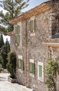 un edificio de piedra con persianas verdes. en Finca Can Beneit, en Binibona