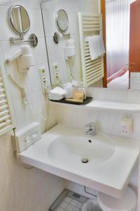 W białej łazience znajduje się umywalka i lustro. w obiekcie Mayers Waldhorn - zwischen Reutlingen und Tübingen w Tybindze