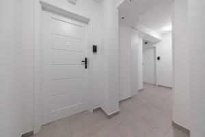 einen Flur mit weißen Türen und Fliesenböden in der Unterkunft TinyRooms in Kattowitz