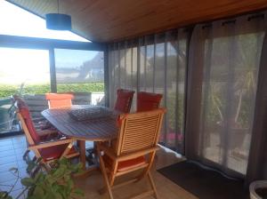 a table and chairs on a screened in porch at Maison vue mer et campagne in Sibiril