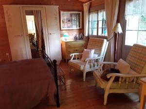 a bedroom with a bed and chairs and a desk at Le chalet de la grenouille verte in Tursac