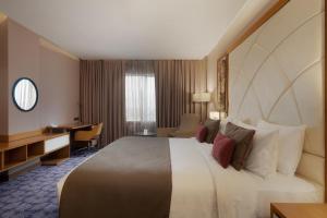 a hotel room with a large bed and a desk at Ramada by Wyndham Erbil Gulan Street in Erbil