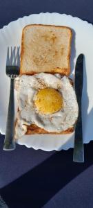 an egg on a piece of bread with a fork and knife at Anugraha Homestay in Rāmnagar