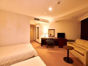 長野市にあるホテルコートランドのベッドとデスクが備わるホテルルームです。