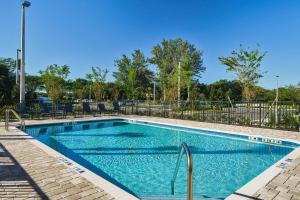 a swimming pool at a resort with blue water at Fairfield by Marriott Inn & Suites Deerfield Beach Boca Raton in Deerfield Beach