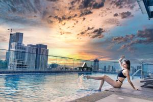 a woman in a bikini sitting on the edge of a swimming pool at Luxcity Hotel & Apartment in Phnom Penh
