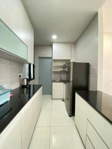 a kitchen with a black refrigerator and white cabinets at P Residence G.L Home Stay in Kuching