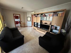 Sala de estar con 2 sillas negras y TV en Casa Sabrina, en Cernusco sul Naviglio