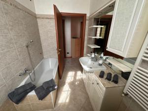 bagno con vasca, lavandino e specchio di Casa Sabrina a Cernusco sul Naviglio