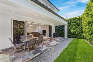 een patio met een tafel, stoelen en gras bij Swainson on Fawnbrake in Henley Beach South