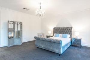 a bedroom with a large bed and a chandelier at Swainson on Fawnbrake in Henley Beach South