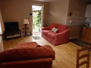 a living room with a red couch and a chair at self-contained private apartment in Barnet