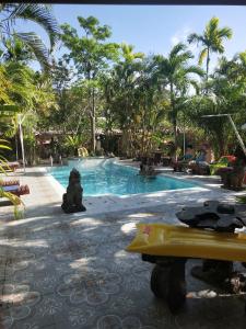 une grande piscine avec des palmiers en arrière-plan dans l'établissement Ban Elephant Blanc Bungalow, à Kata Beach
