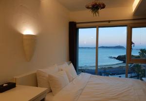 a bedroom with a bed and a view of the ocean at Chuidasun Resort Tea & Meditation in Seogwipo