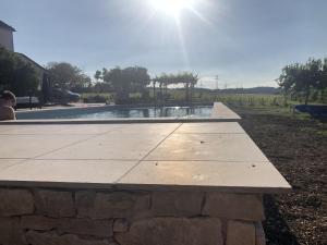 a stone bench in front of a pool of water at La Petite maison de Céline & Frédéric avec piscine à Préhy in Préhy +3 photos
