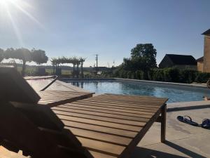 a swimming pool with a wooden deck and water at La Petite maison de Céline & Frédéric avec piscine à Préhy in Préhy