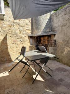 einen Tisch und zwei Stühle vor einem Steinkamin in der Unterkunft Belle vue in Gourdon-en-quercy