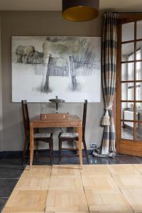 a dining room with a wooden table and two chairs at vakantiehuis ter poele in Avelgem