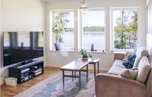 a living room with a couch and a tv and windows at 3 Bedroom Awesome Home In rebro in Örebro