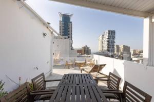 d'une terrasse sur le toit avec une table et des chaises en bois. dans l'établissement Boho Vibe - Penthouse, à Tel Aviv