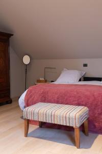 1 dormitorio con 1 cama con manta roja y banco en vakantiehuis ter poele, en Avelgem