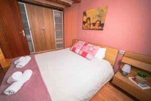 バルセロナにあるRustic Poble Sec Apartmentのピンクの壁の小さなベッドルーム(白いシーツ付きのベッド1台付)