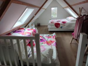 a attic bedroom with two beds and two windows at de Klaproos in Noordgouwe
