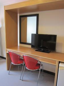a desk with two red chairs and a flat screen tv at Nichols Airport Hotel in Manila