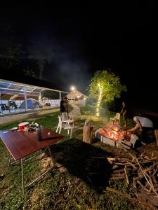Byrahalli Bliss riverside camping في ساكليشبور: مجموعة من الناس تقف حول النار في الليل