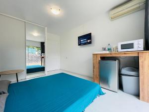 a small room with a blue bed and a microwave at REA Lodge in Punaauia