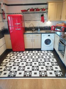 eine Küche mit einem roten Kühlschrank und einem schwarz-weißen Boden in der Unterkunft Watermark Apartments in Whitby